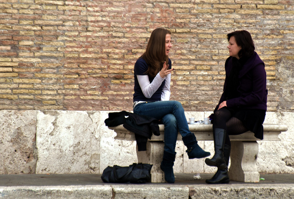 Two women conversing on a bench.