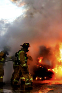 Firefighters putting out a car fire.